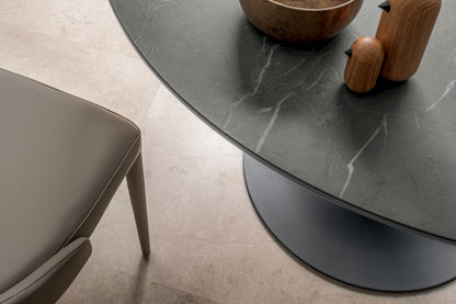 Round dining table with green ceramic top and copper pedestal base