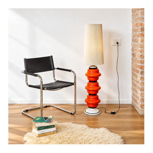 Modern cantilever armchair upholstered in black leather with a polished chrome tubular steel frame, displayed beside a contemporary floor lamp.