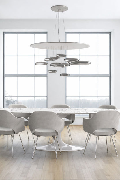 Round tulip dining table with upholstered chairs in a minimalist modern Italian dining room featuring large windows and sculptural ceiling light