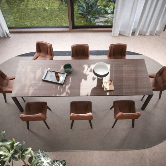 Modern rectangular walnut wood dining table with tapered legs, surrounded by six upholstered dining chairs in a contemporary dining room with floor-to-ceiling windows.