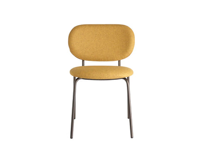 Front view of a mustard upholstered dining chair with a rounded backrest, padded seat, and slim dark metal frame.