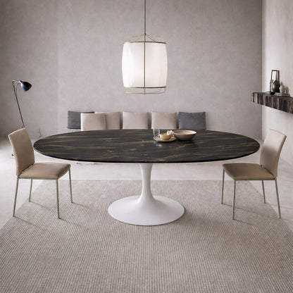 Extendable oval tulip dining table with Noir Desir ceramic black top and white pedestal base, shown open with extension leaves in a modern minimalist dining room.
