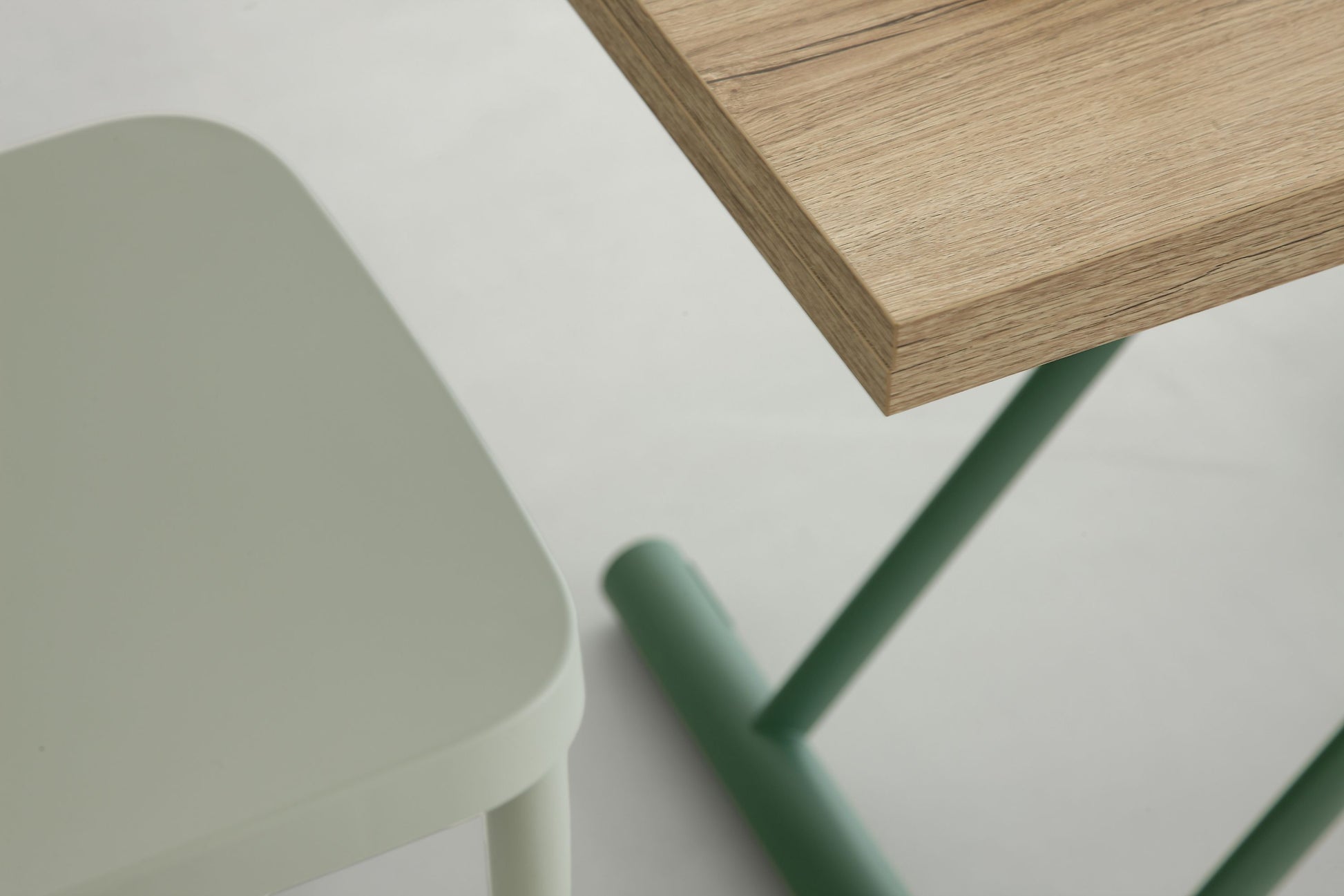 Oak dining table with green metal base in bright modern living space with chairs