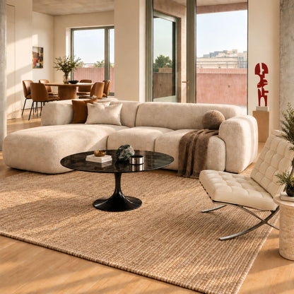 Obsidian Luxe Tulip coffee table featuring a smooth glossy black liquid laminate tabletop paired with a matching glossy black tulip pedestal base, styled in a contemporary living room with a curved cream sofa, woven rug, designer lounge chair, and warm natural daylight. A luxury Italian designer coffee table for modern, Scandinavian, and mid-century interiors.