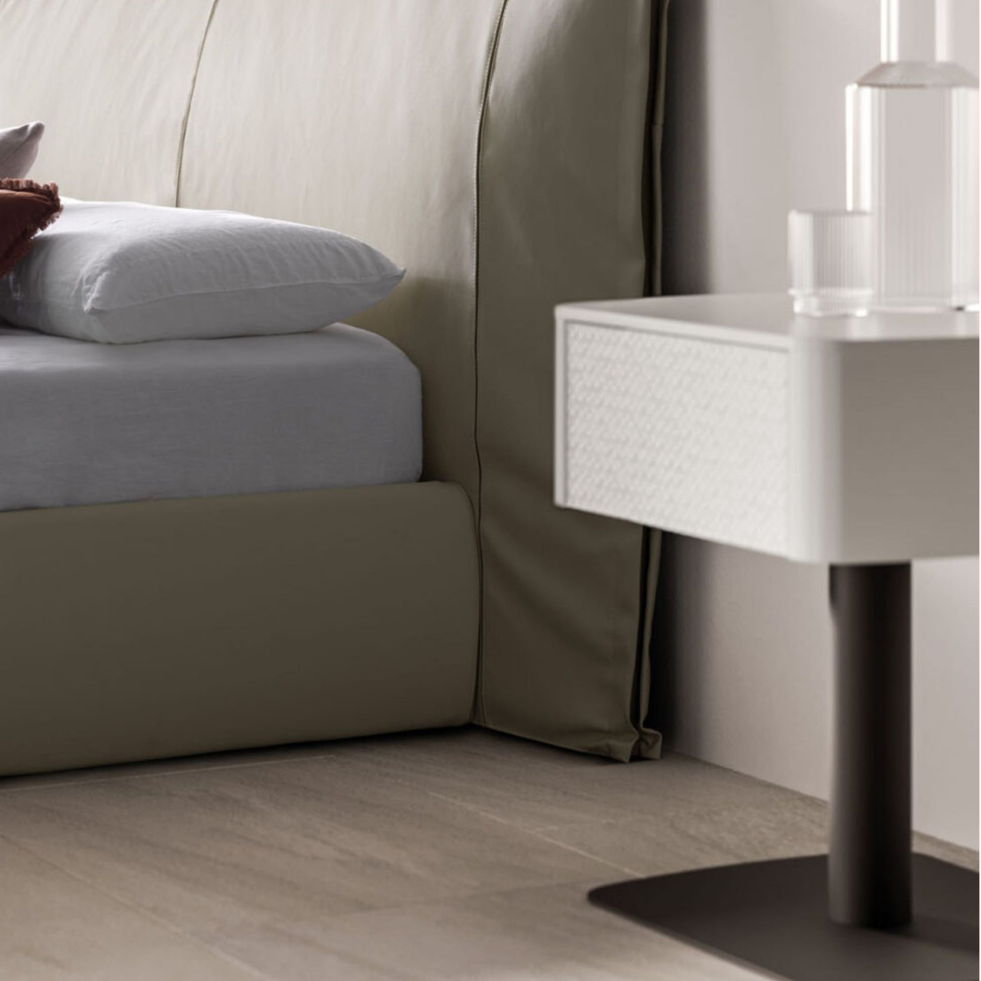 Neatly made bed with white bedding and pillows, next to a modern nightstand.