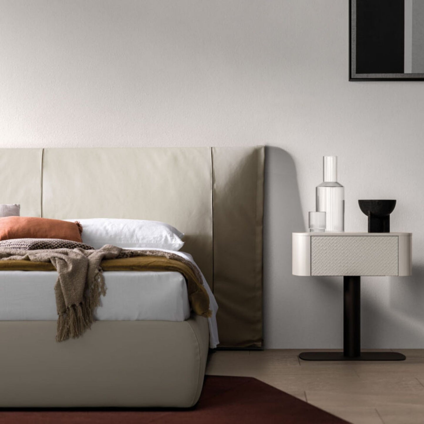 Modern bedroom with beige upholstered bed and side table against a gray wall.