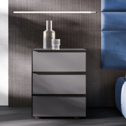 Gray nightstand with two drawers against a textured wall with a blue cushioned headboard.