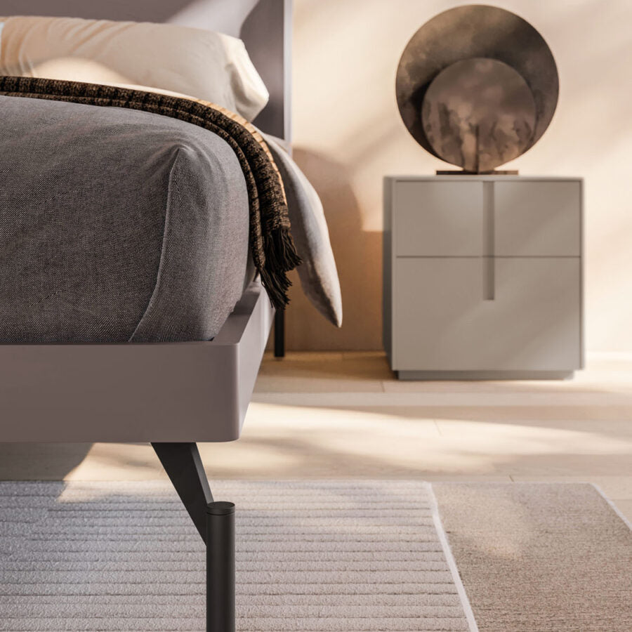 Gray upholstered bed with a nightstand in a bedroom setting