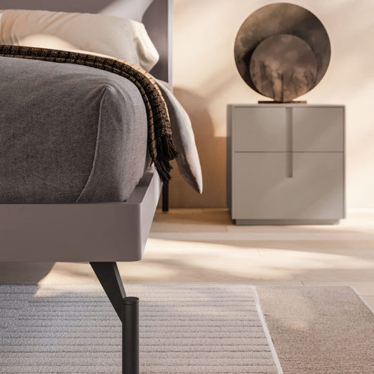Gray upholstered bed with a nightstand in a bedroom setting