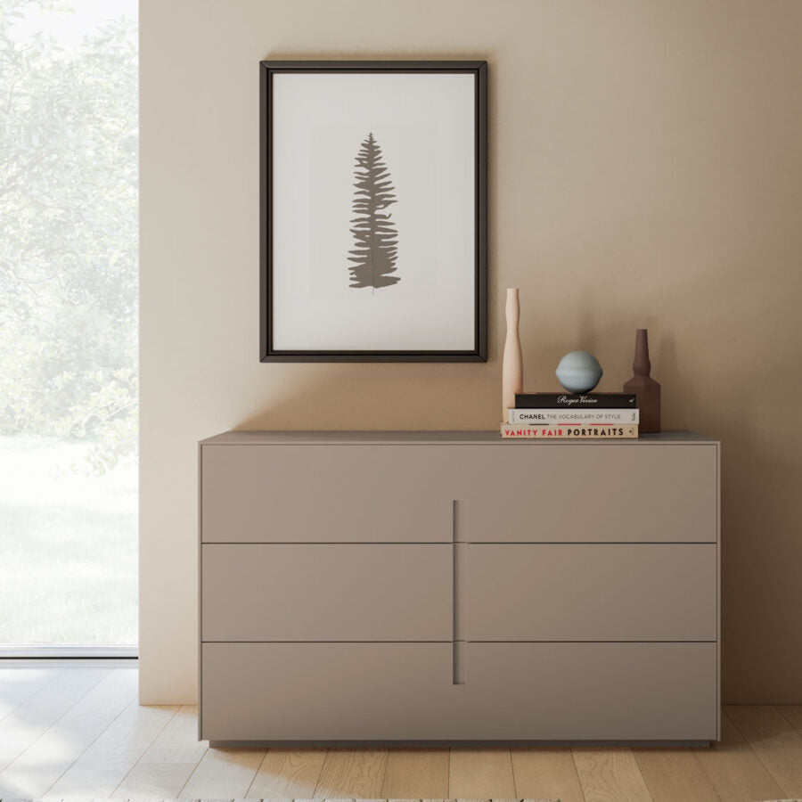 Beige dresser with decorative items against a beige wall with a framed picture.