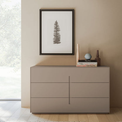 Beige dresser with decorative items against a beige wall with a framed picture.