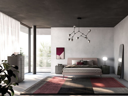 Modern bedroom with a bed, rug, and decorative elements.