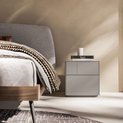 Modern bedroom with a bed and nightstand against a beige wall.