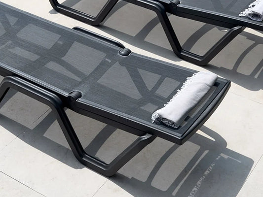 Close-up of a black outdoor sun lounger with breathable mesh fabric, adjustable backrest, and integrated wheels.