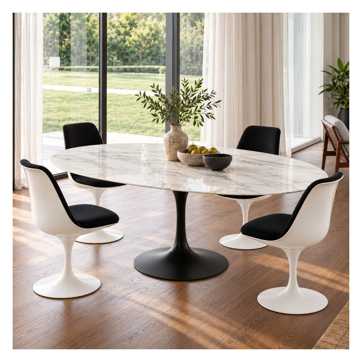 Oval white marble Tulip dining table with a black pedestal base, surrounded by white chairs with black seats in a bright, windowed dining room.