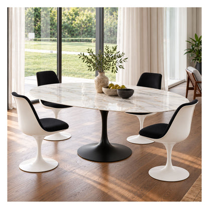 Oval white marble Tulip dining table with a black pedestal base, surrounded by white chairs with black seats in a bright, windowed dining room.