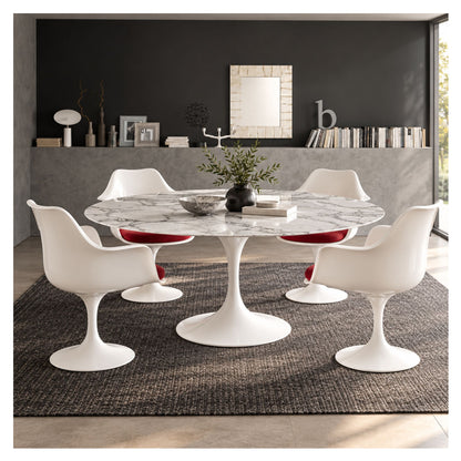 Oval white marble Tulip dining table with a white pedestal base, surrounded by four white chairs with red cushions in a modern dining room.