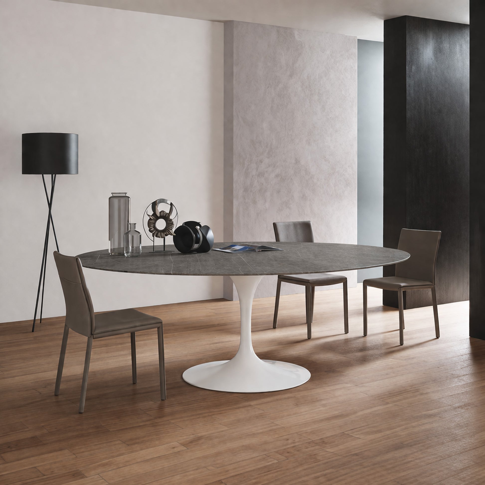Oval tulip table Saarinen style with dark ceramic top and white pedestal base in modern dining room