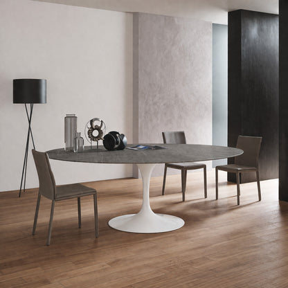 Oval tulip table Saarinen style with dark ceramic top and white pedestal base in modern dining room