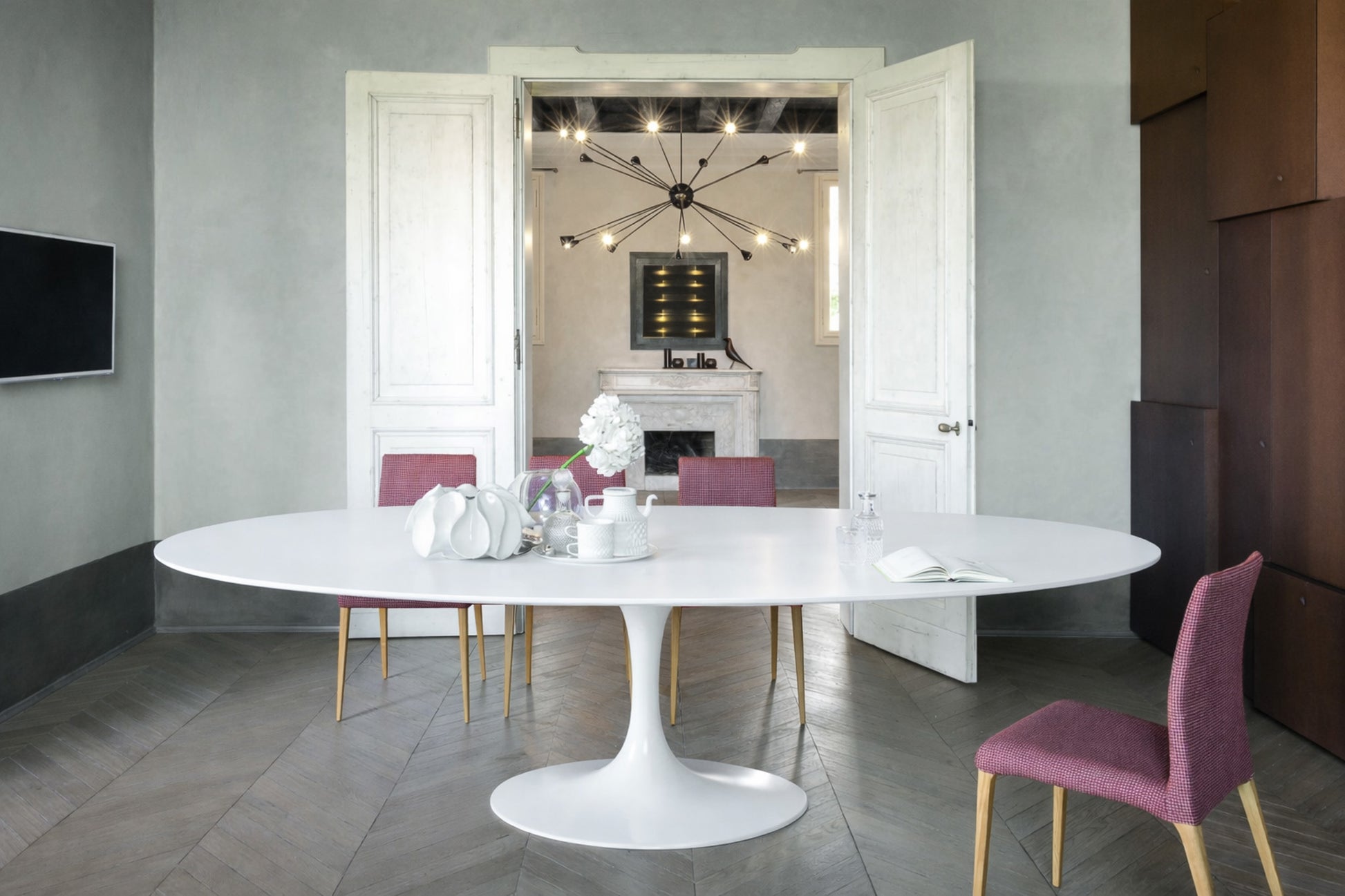 Oval tulip table Saarinen style with white top in elegant modern dining room with upholstered chairs
