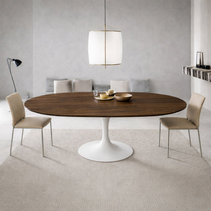 Modern dining room with round walnut tulip dining table and white pedestal base paired with beige upholstered chairs in a minimalist interior