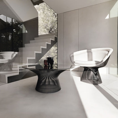 Modern Platner wire armchair with white upholstered seat paired with a matching black wire coffee table in a contemporary minimalist living room.