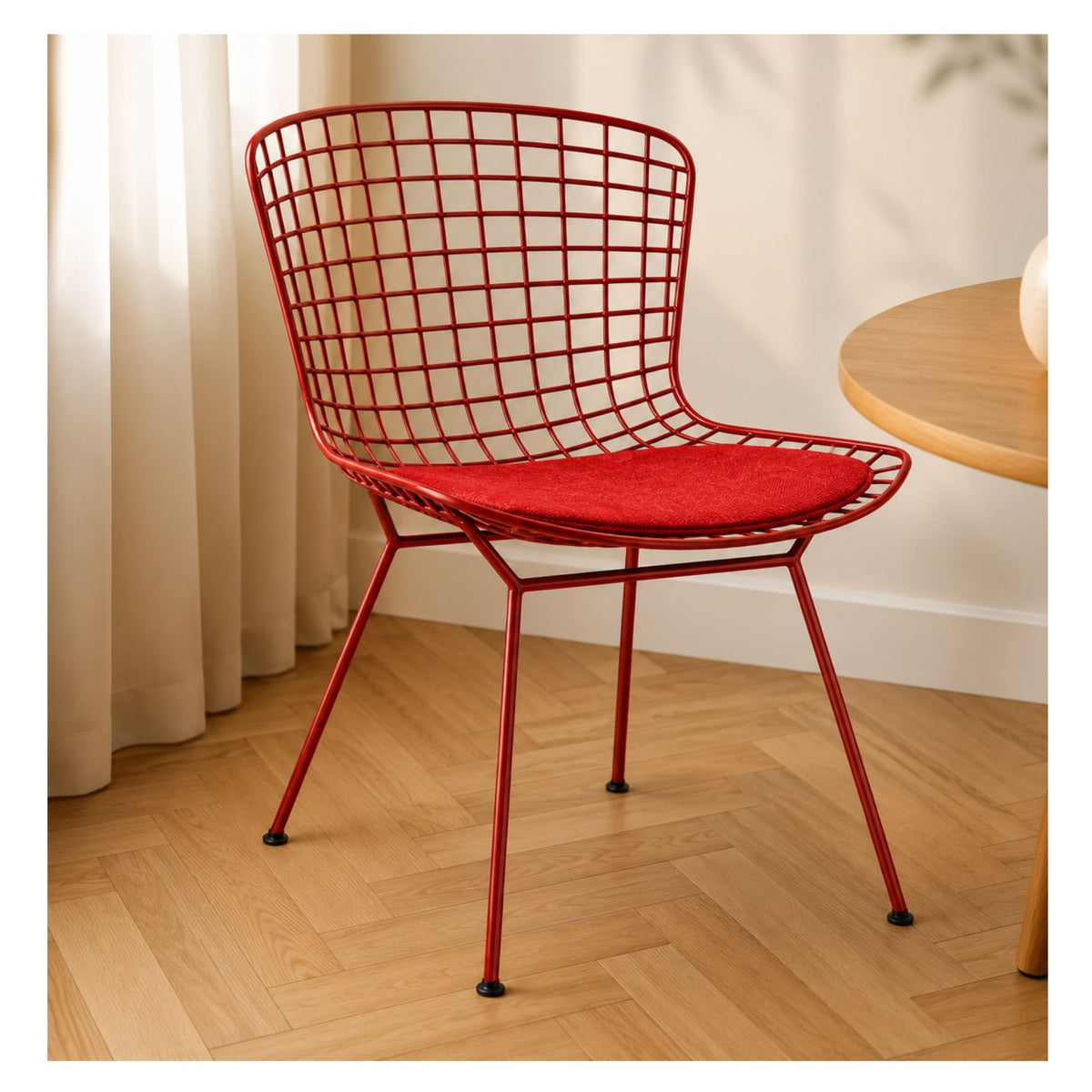 Red steel wire dining chair with a red seat cushion beside a wooden table