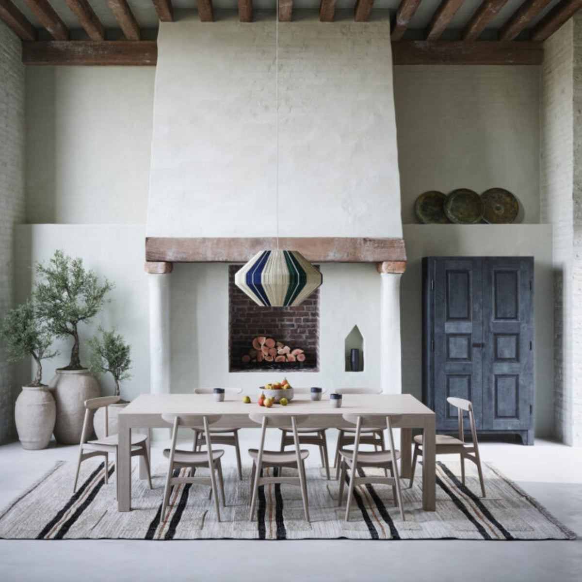 Round dark walnut pedestal dining table with a black tulip base styled in a modern luxury living room with neutral décor.