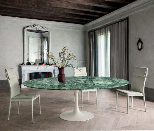Round green marble dining table with white pedestal base in a classic interior, styled with upholstered chairs and decorative centerpiece