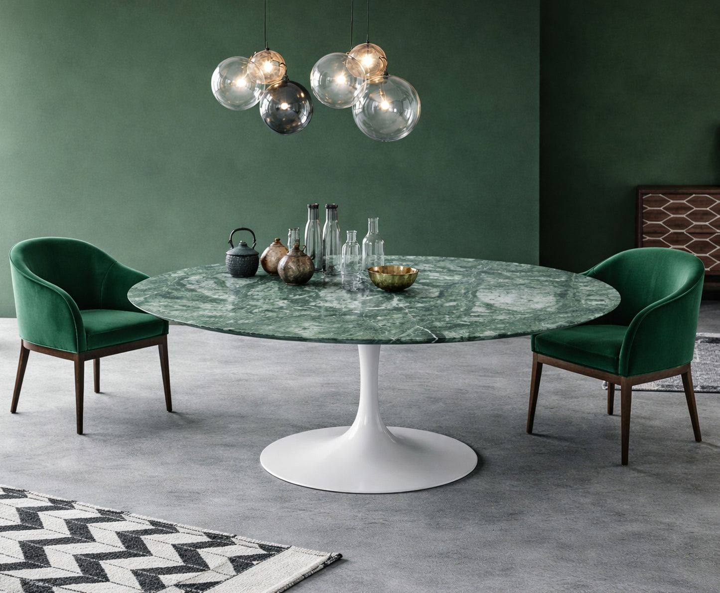 Round green marble dining table with white pedestal base in a modern green interior, styled with green upholstered chairs and glass globe pendant lighting