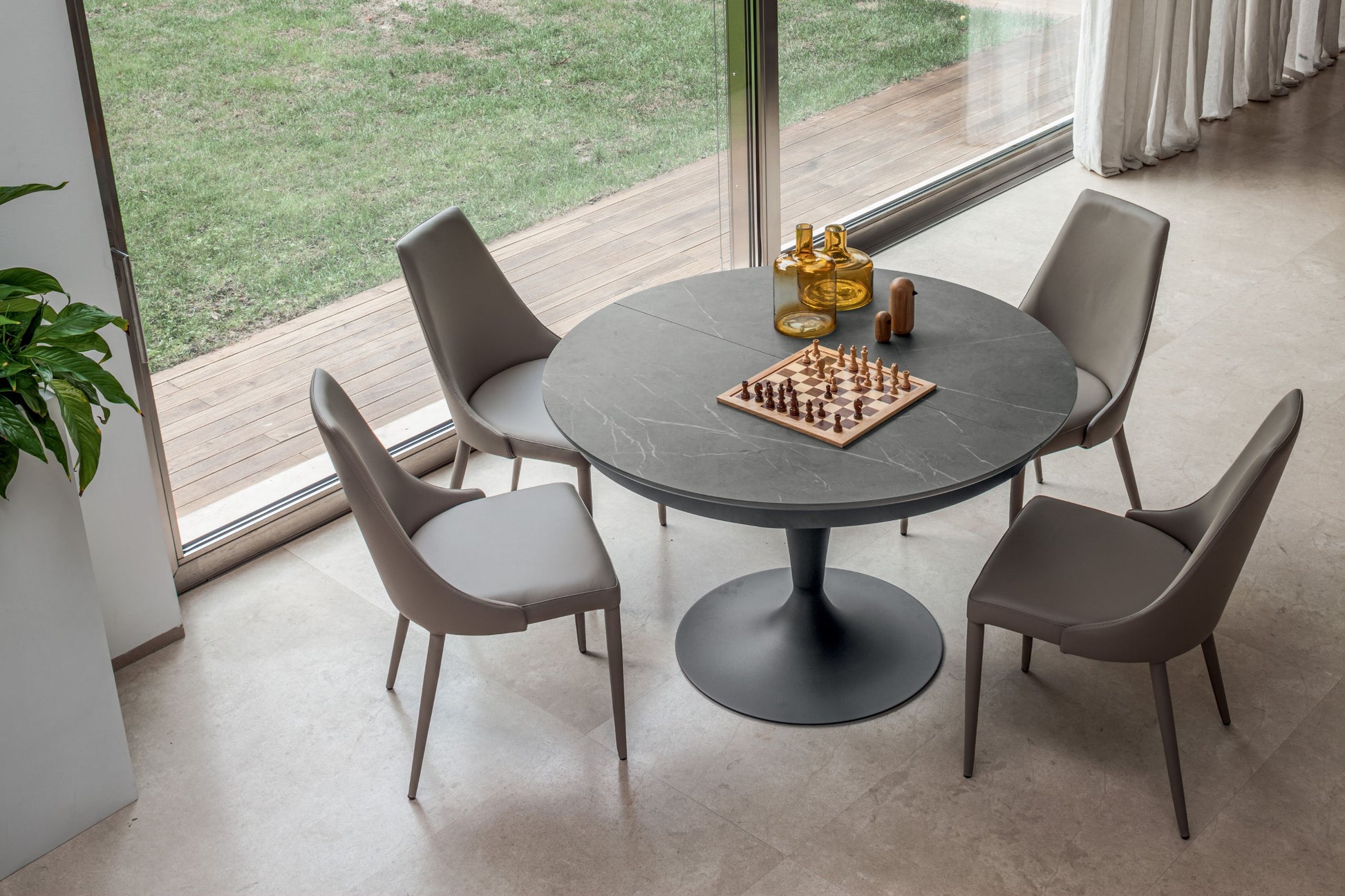 Round pedestal dining table with marble effect top and black base seating four
