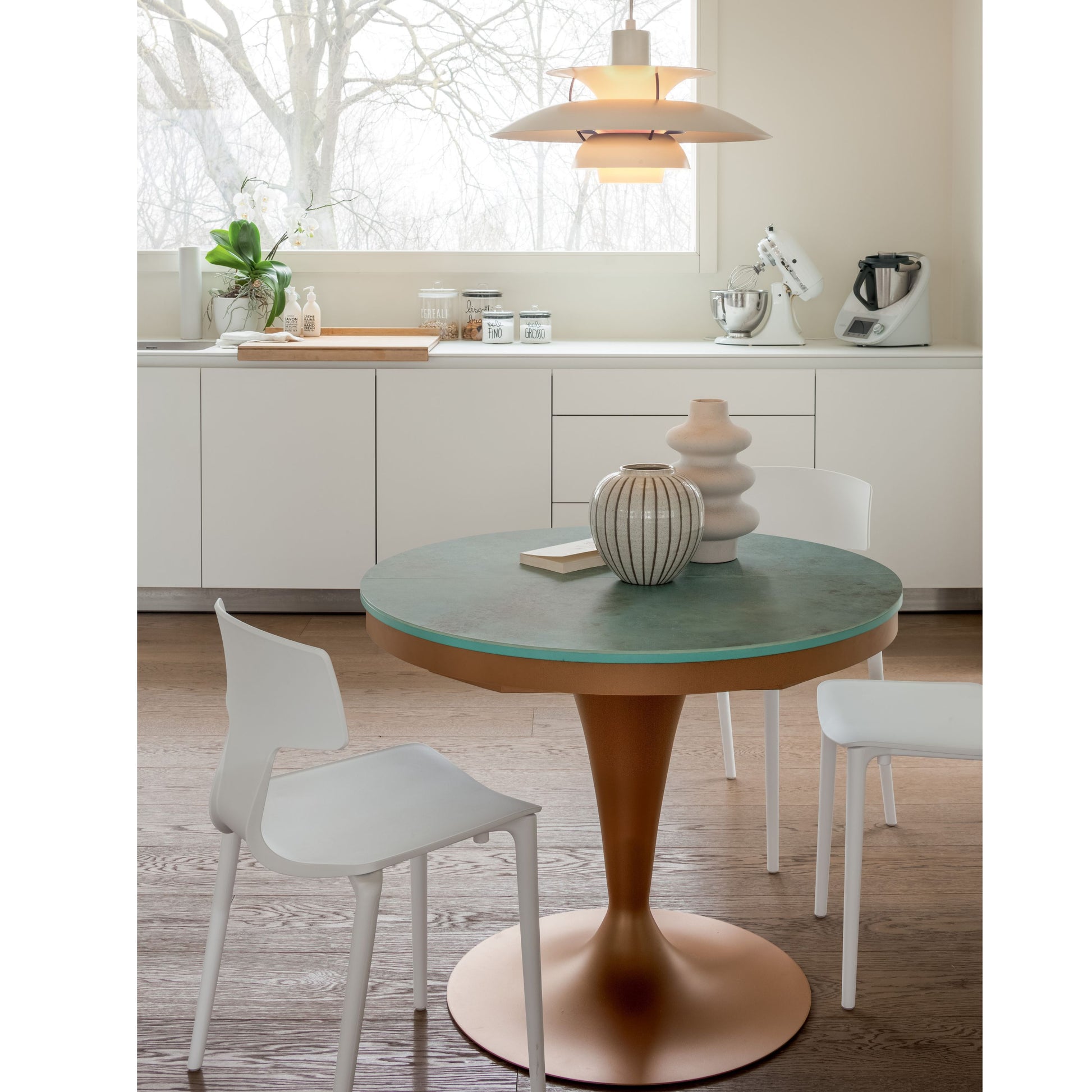 Round pedestal dining table with green ceramic top and copper pedestal base