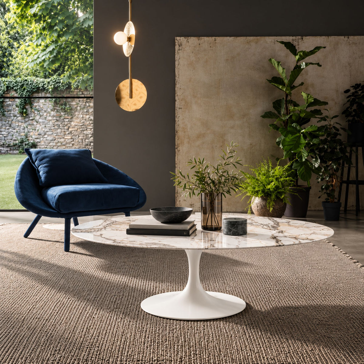 Round tulip coffee table with a white marble-effect top and white pedestal base in a contemporary living room with modern furniture and indoor plants.