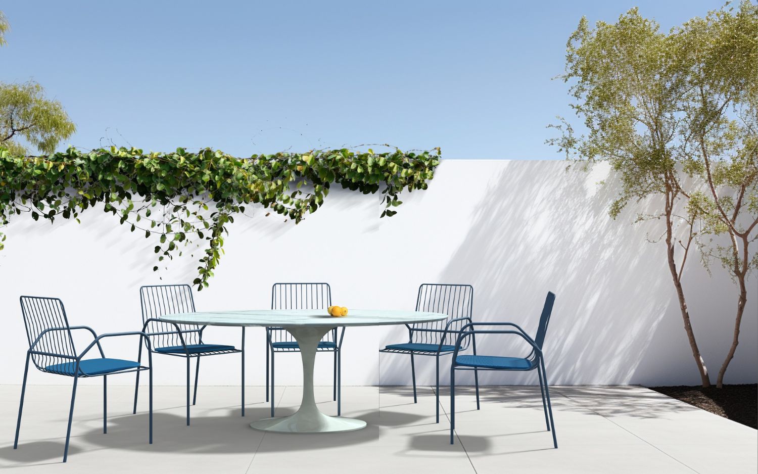 Round tulip outdoor dining table with weather-resistant top and white pedestal base, styled with matching chairs on a modern patio setting