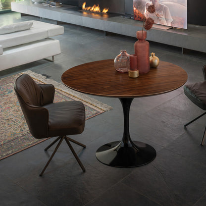 Round tulip table Saarinen style with walnut wood top and black pedestal base in modern living room