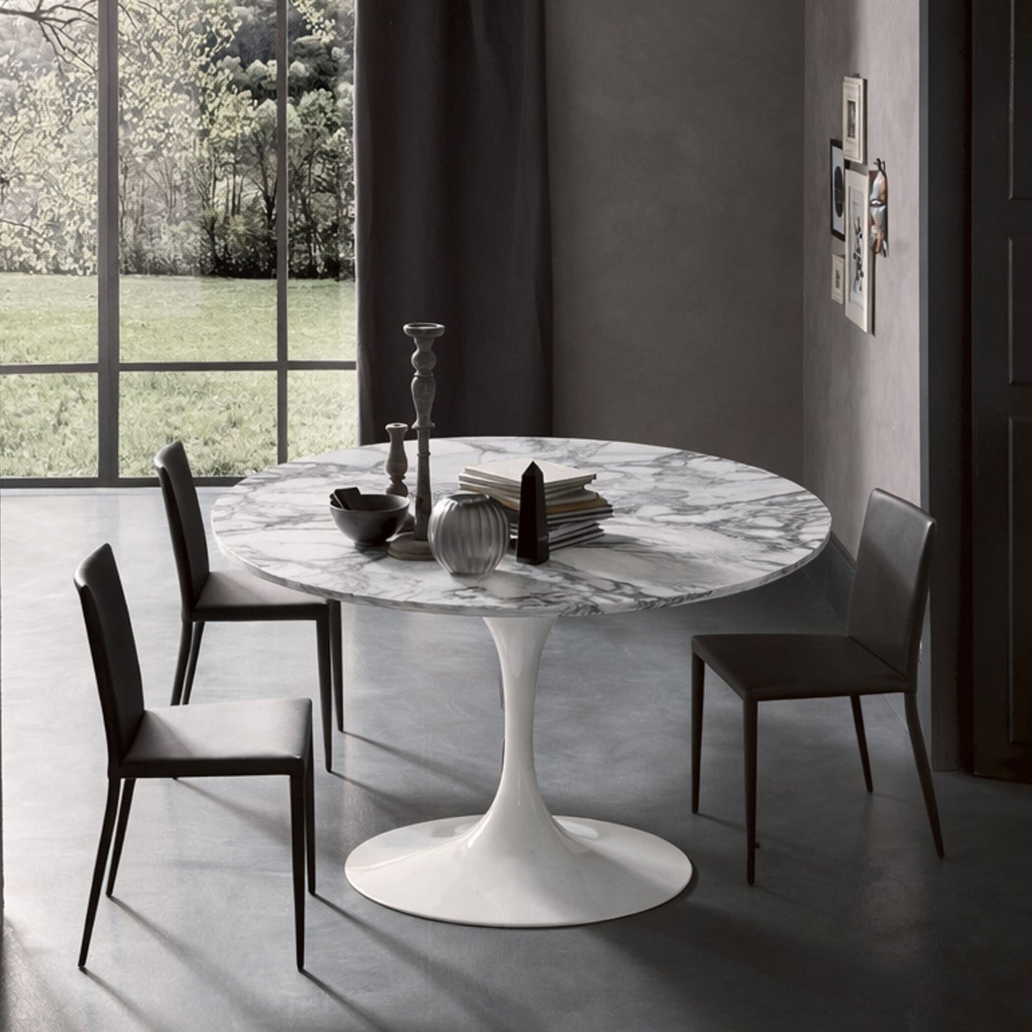 Round tulip table Saarinen style with white marble top near large window in modern dining room