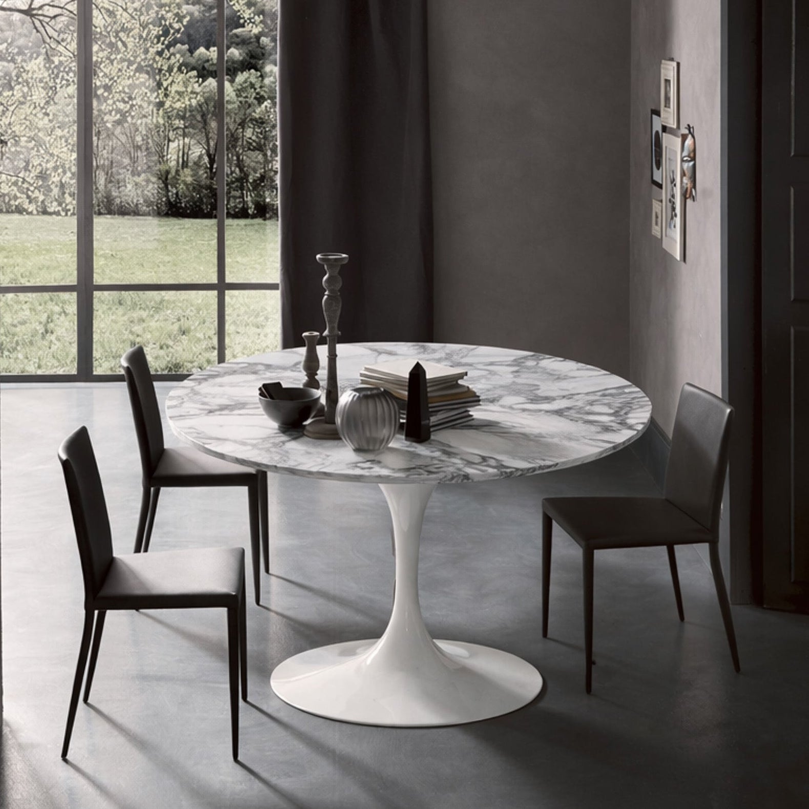 Round tulip table Saarinen style with white marble top near large window in modern dining room