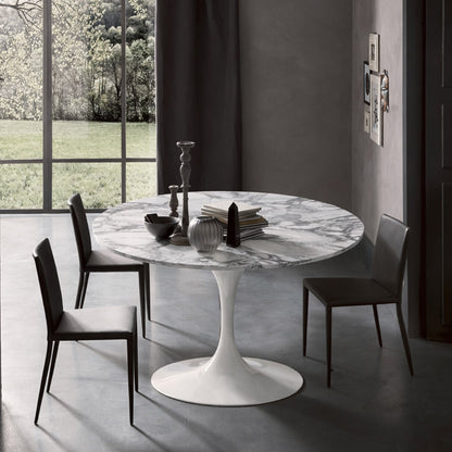 Round tulip table Saarinen style with white marble top near large window in modern dining room
