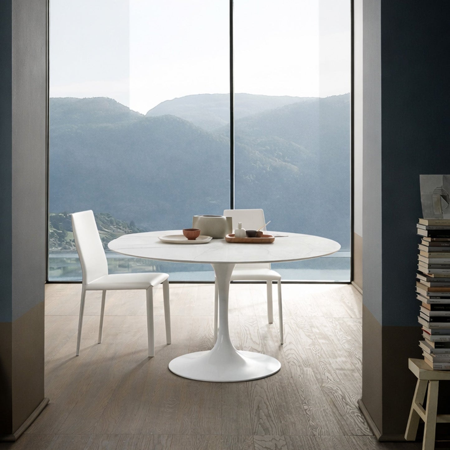 Round tulip table Saarinen style with white top in modern dining room with lake view