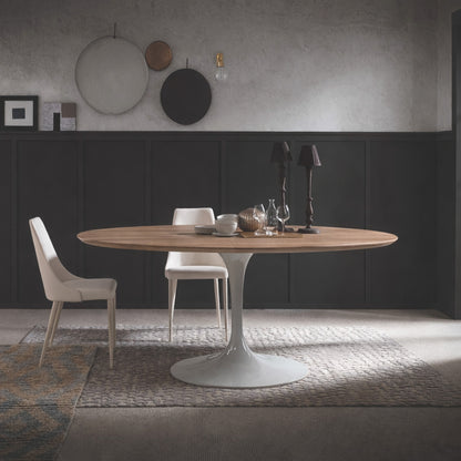 Round walnut tulip dining table with white pedestal base paired with beige upholstered chairs in a modern dining room