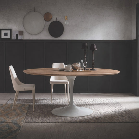 Round walnut tulip dining table with white pedestal base paired with beige upholstered chairs in a modern dining room