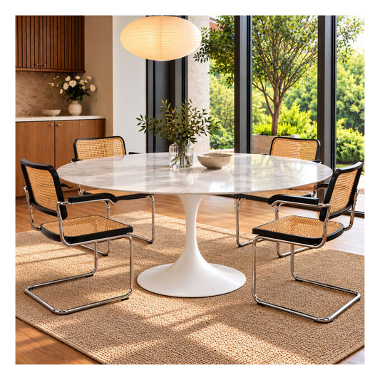 Round white marble-effect ceramic Tulip dining table with a sculptural pedestal base, styled with four cane and chrome chairs in a bright modern dining room.