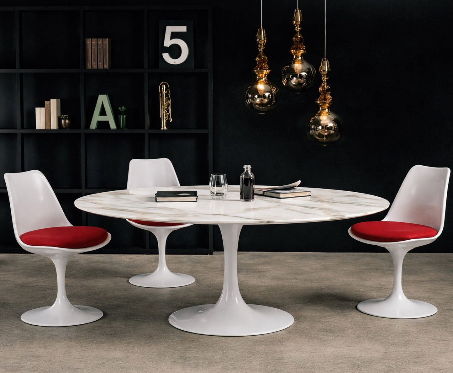 Round white marble dining table with white pedestal base in a dark modern interior, styled with white chairs with red seat cushions, black shelving and glass pendant lighting