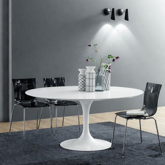 Round white marble dining table with white pedestal base in a modern dark interior, styled with black chairs, grey wall and wall-mounted lighting