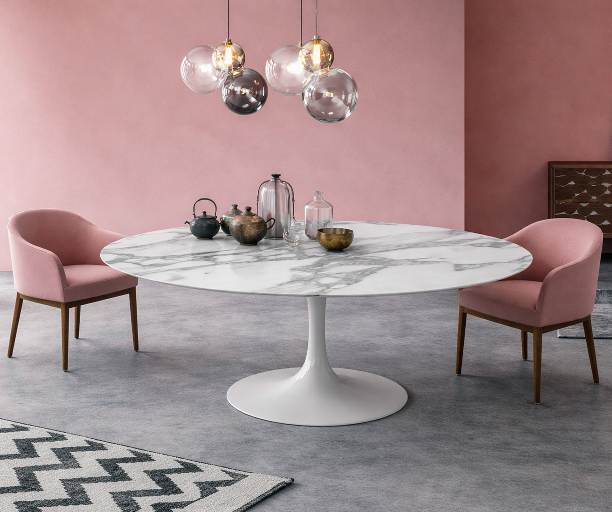 Round white marble dining table Saarinen style with white pedestal base in a modern pink interior, styled with pink upholstered chairs and glass pendant lighting