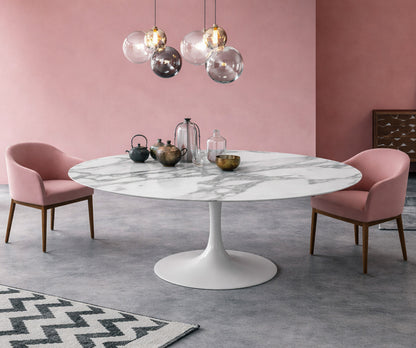 Round white marble dining table Saarinen style with white pedestal base in a modern pink interior, styled with pink upholstered chairs and glass pendant lighting