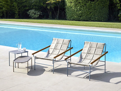 S•CAB Dress Code Glam outdoor armchairs with quilted fabric and iroko wood armrests beside a modern swimming pool, creating a stylish luxury outdoor seating area