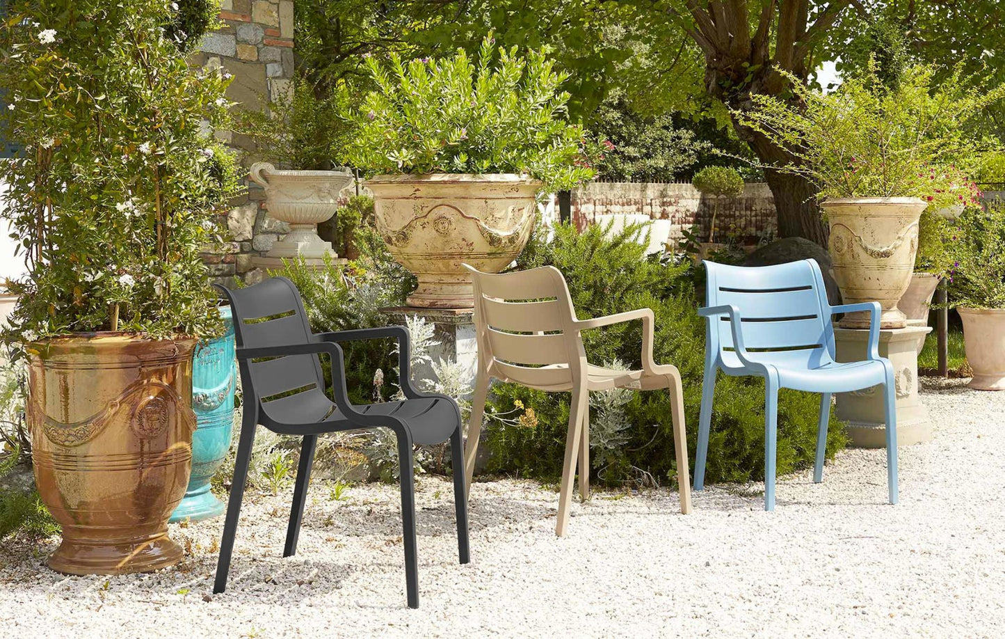 SCAB Sunset Italian outdoor armchairs in graphite, dove grey and light blue displayed in a Mediterranean garden with decorative planters.