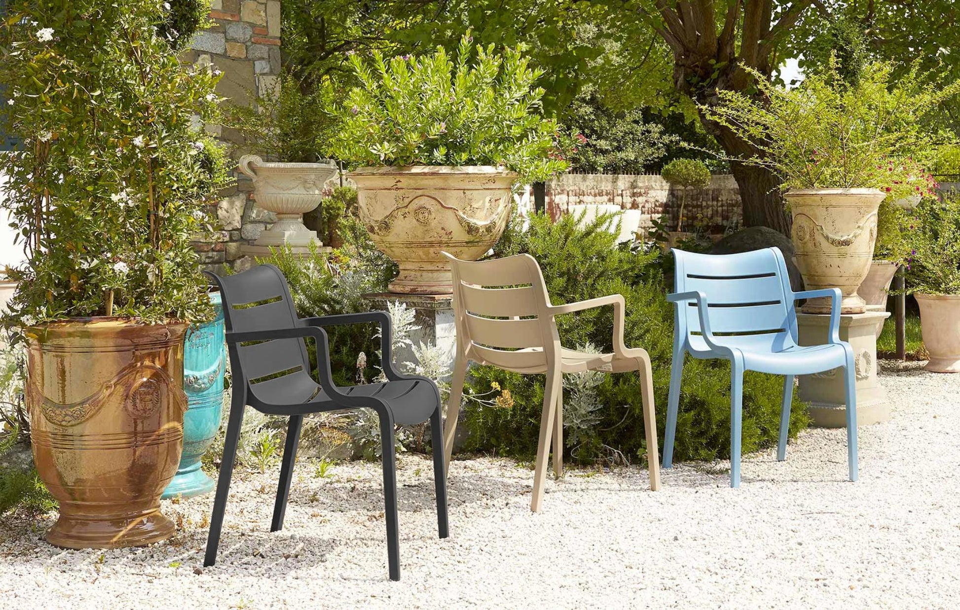 SCAB Sunset Italian outdoor armchairs in graphite, dove grey and light blue displayed in a Mediterranean garden with decorative planters.