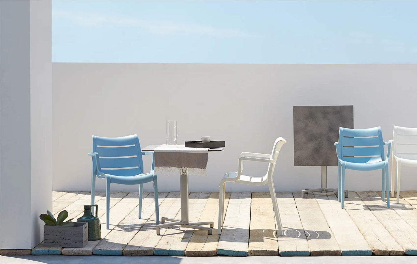 SCAB Sunset stackable outdoor armchairs around a café table on a modern terrace, suitable for residential and commercial outdoor spaces.